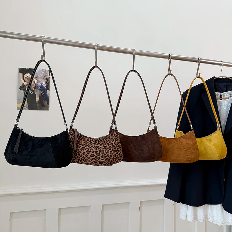 Minimal black suede 90s baguette shoulder bag hanging with other color variations.