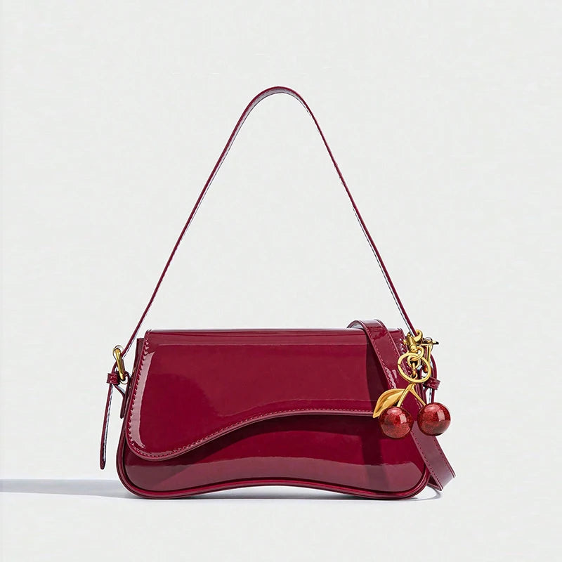Red handbag with gold accents and cherry decorations on a white background